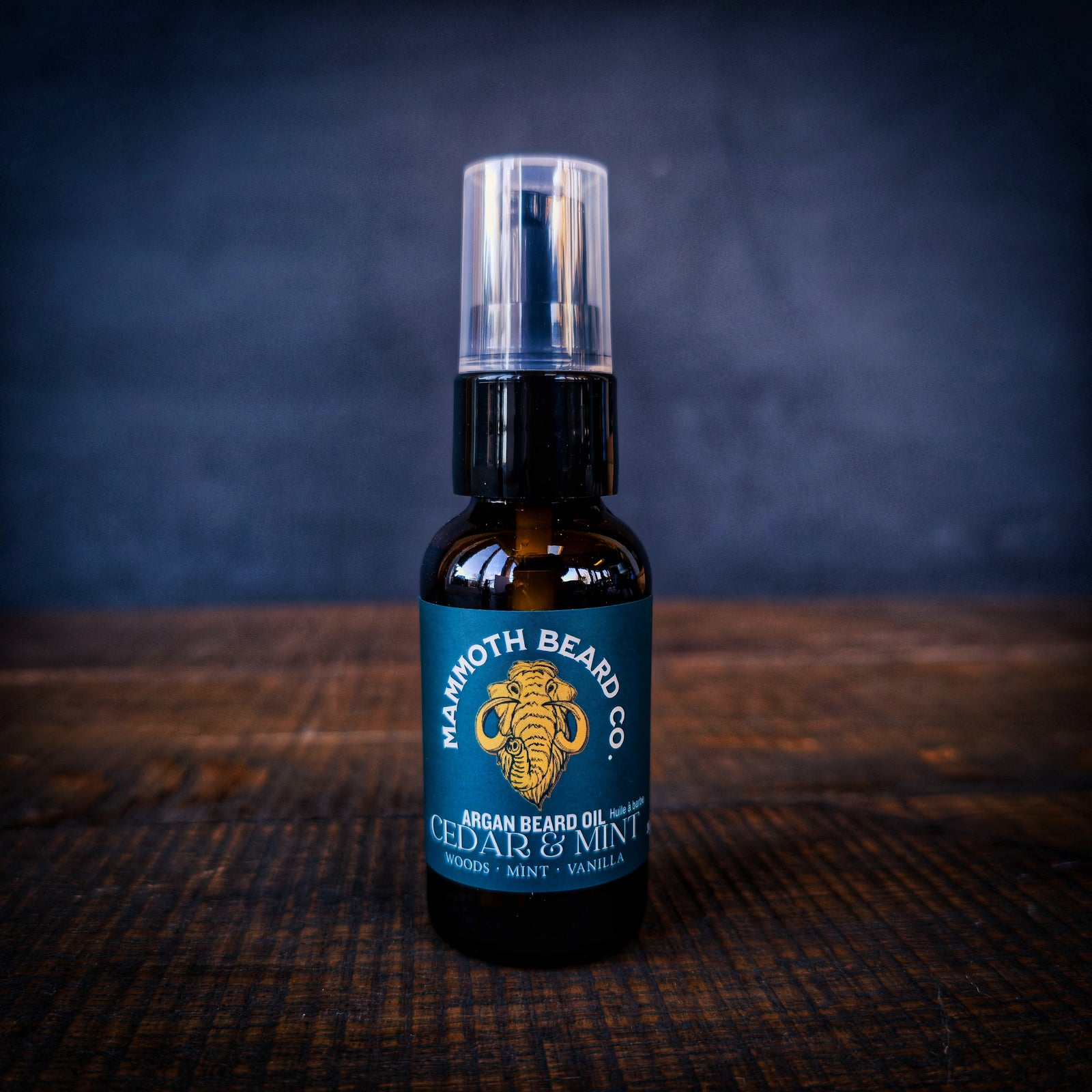 Mammoth Beard Co Cedar & Mint Argan Beard Oil in amber glass bottle with pump on rustic wood background, natural beard conditioning oil with woods, mint and vanilla notes.