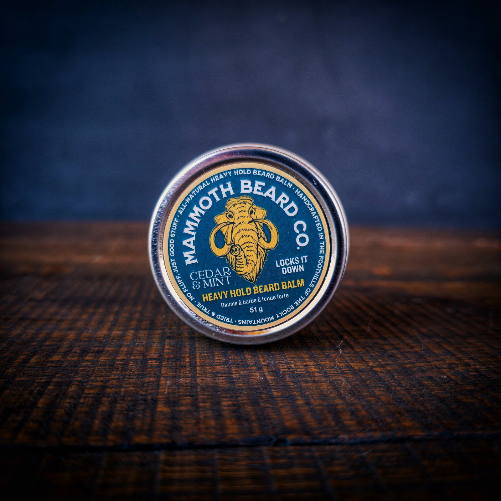 Mammoth Beard Co Cedar & Mint Heavy Hold Beard Balm tin on wooden background, strong hold natural beard styling balm locks beard in place.