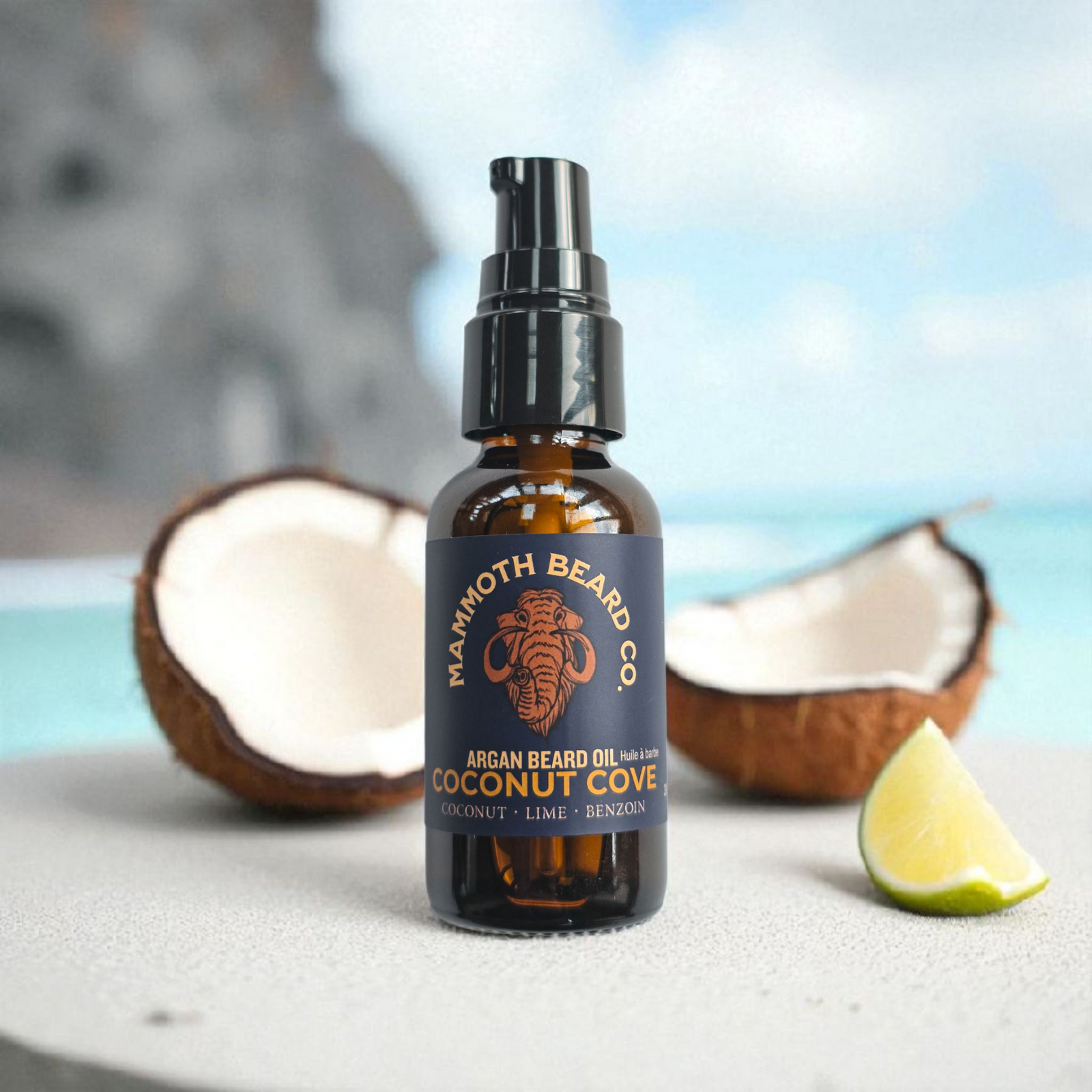 Bottle of Maxmoth Beard Co. Argan Beard Oil with coconuts and a lime wedge on a blurred beach background