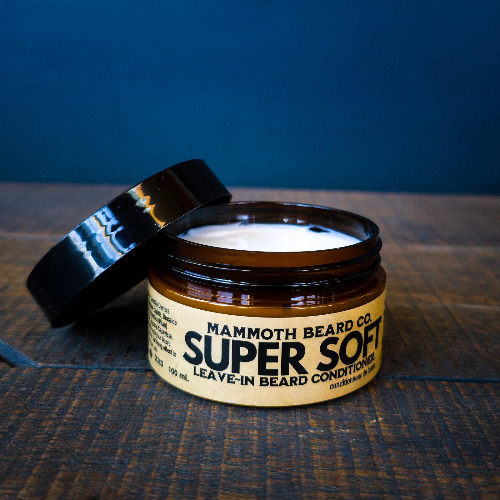 Mammoth Beard Co. Super Soft leave-in beard conditioner jar on a textured surface with a blue background