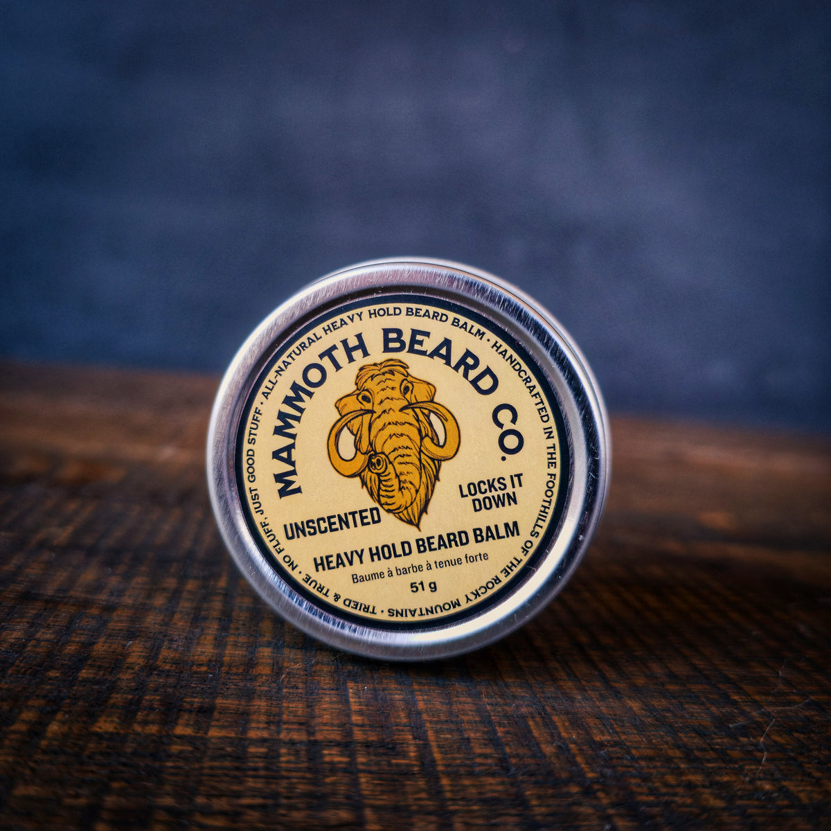 Mammoth Beard Co. heavy hold beard balm container on a textured surface with a dark background