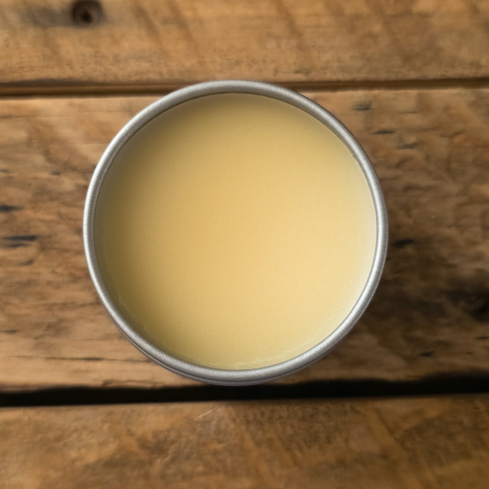 Close-up of Mammoth Beard Co. beard balm in a metal tin, showing its creamy texture ready to be scooped and applied for conditioning and styling.