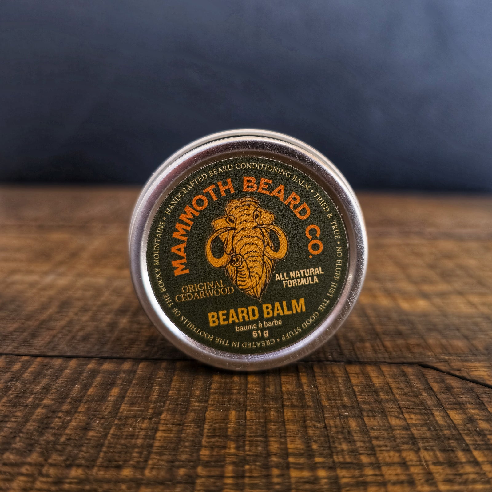 Mammoth Beard Co. Original Cedarwood beard balm container on a wooden surface with a dark background