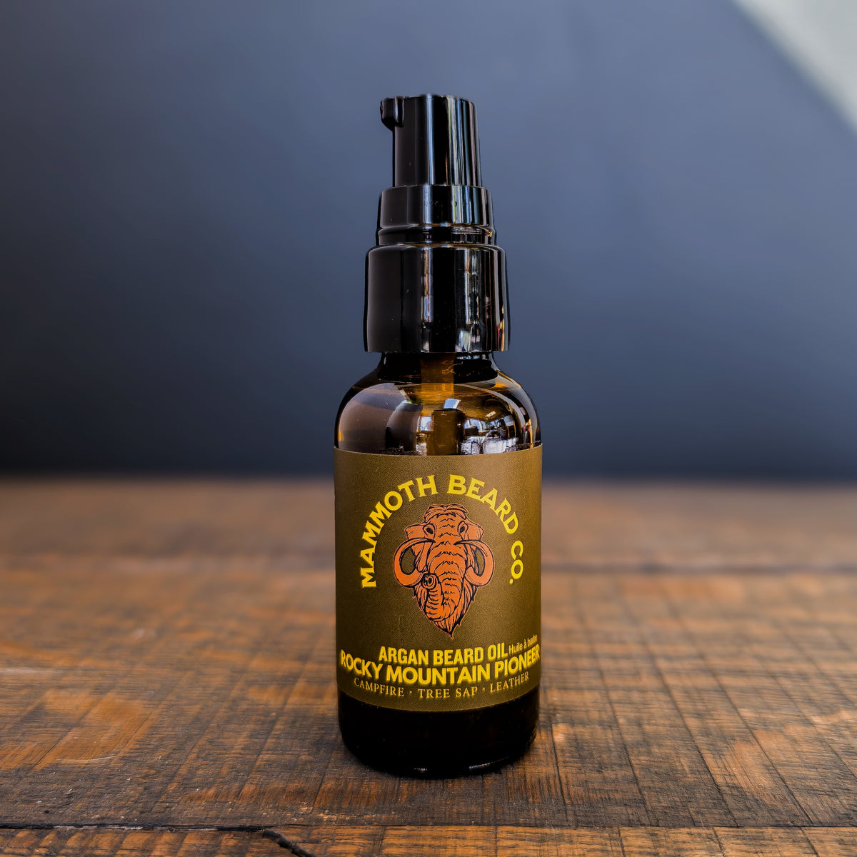 Mammoth Beard Co. argan beard oil bottle on a wooden surface with a dark background