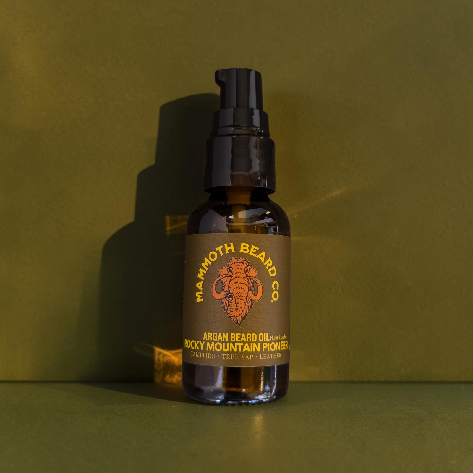 Bottle of Mammoth Beard Co. argan beard oil on a green background