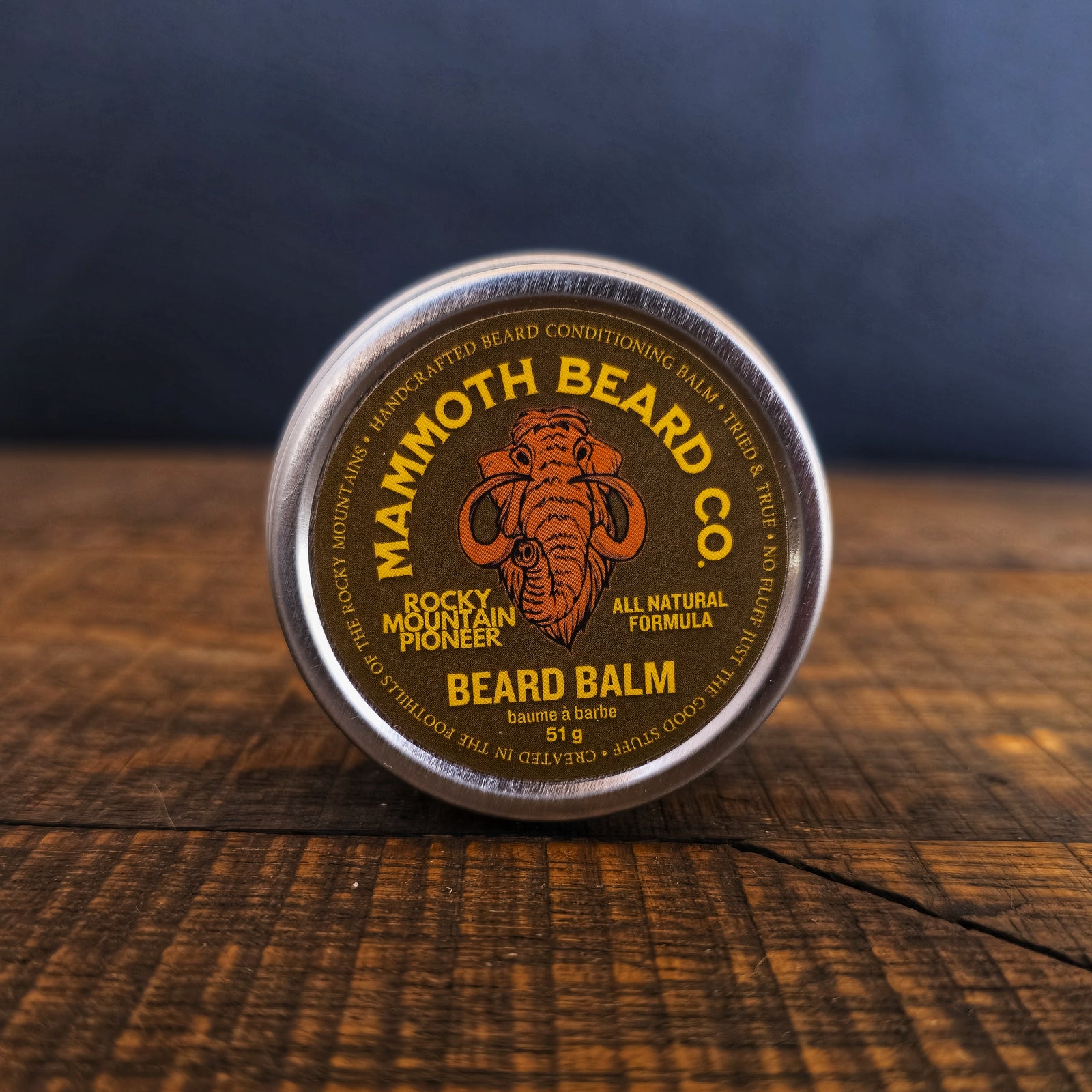 Mammoth Beard Co. beard balm container on a wooden surface with a dark background