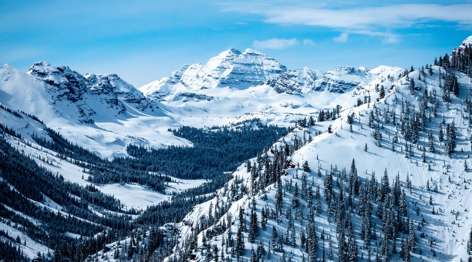 Snow-covered mountains with a clear blue sky depicting the feel of Mammoth Beard Cedar & Mint scent