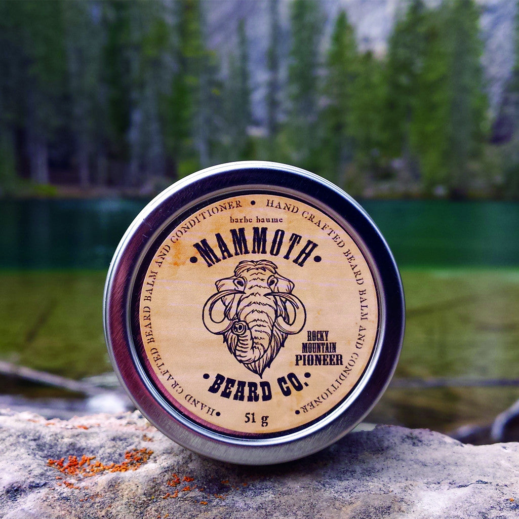 A container of Mammoth Beard Co. balm set against a natural backdrop of Grassi Lakes in Kananaskis country.